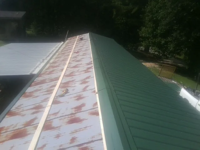 Old rusted panels beside newly installed green metal roofing — Wind Damage Roof Repair by Roofing Brothers in Kirtland Afb