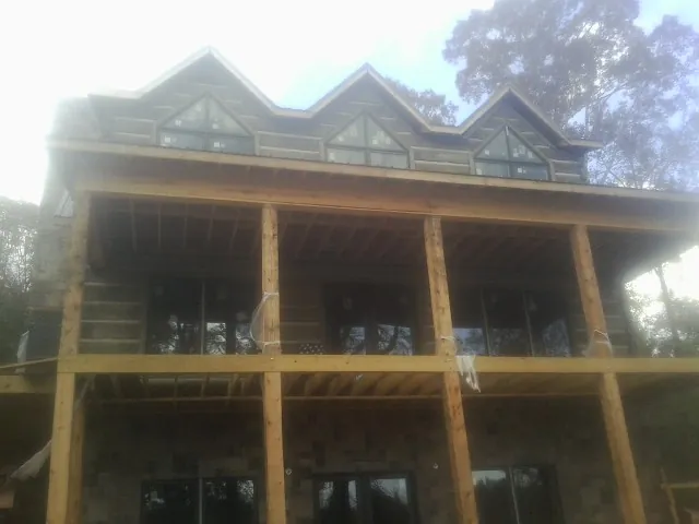 Dormers and porch framing on a large log home under construction — Roof Coating work by our crew in Kirtland Afb
