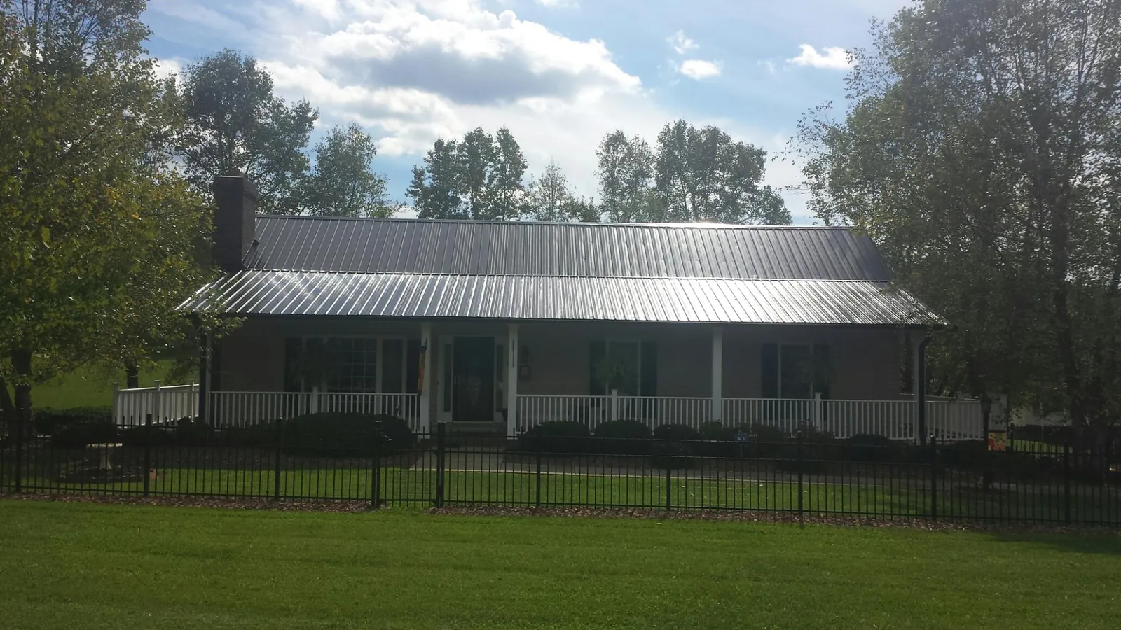 Gray metal roof on a brick ranch with a full width front porch — Gutter Guard Installation work by our crew in Kirtland Afb