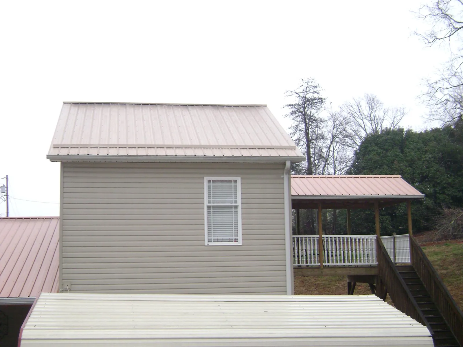 Tan metal roofs on a two story addition and attached porch, from a Roof Replacement job in Kirtland Afb