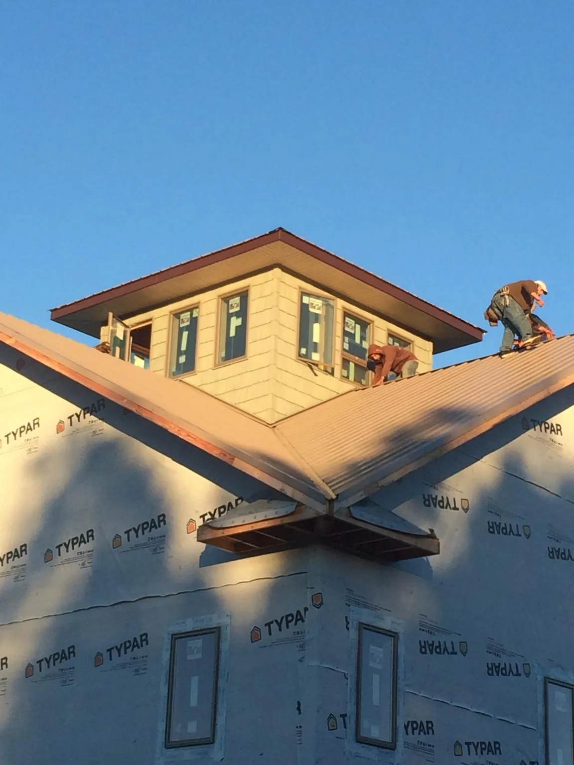 Roofers working around a rooftop cupola on a new metal roof at sunset — Roof Waterproofing in Kirtland Afb by Roofing Brothers